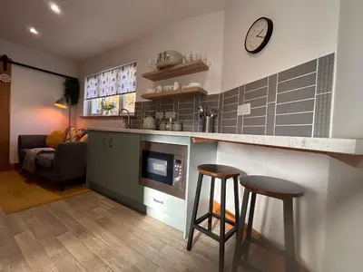 a kitchen with two bar stools and a clock on the wall at Glenshee Annexe, Oban. in Oban