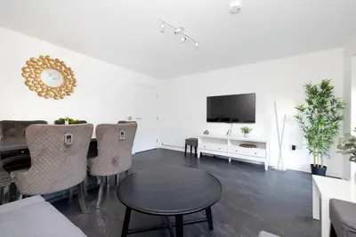 a living room with a table and chairs and a tv at Stylish 3BR Home with Garden & Free Parking - Near O2 Academy & City Centre in Glasgow