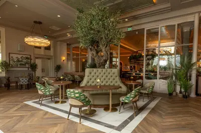 a lobby with tables and chairs and a tree at Crieff Hydro Self Catering in Crieff