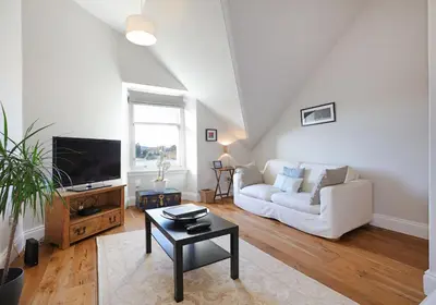 a living room with a white couch and a tv at The Botanics Residence in Edinburgh