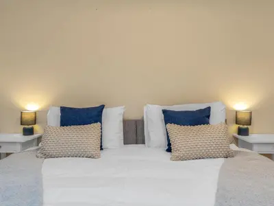 a large bed with blue and white pillows and two lamps at Cheerful Stays: 4 Bedroom Cottage in Arrochar in Arrochar