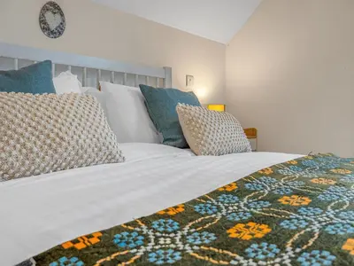 a bedroom with a large white bed with pillows at Cheerful Stays: 4 Bedroom Cottage in Arrochar in Arrochar