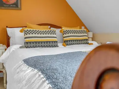 a bedroom with a bed with white sheets and pillows at Cheerful Stays: 4 Bedroom Cottage in Arrochar in Arrochar