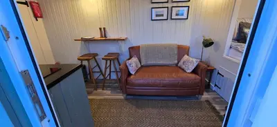 a living room with a brown chair and a stool at North Muasdale Farm - Byre View in Muasdale