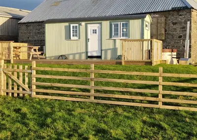 a wooden fence in front of a house at North Muasdale Farm - Byre View in Muasdale