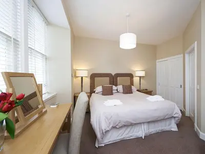 a bedroom with a white bed and a desk and a table with flowers at Home Farm Cottages, Glendaruel, Argyll. Scotland in Clachan of Glendaruel