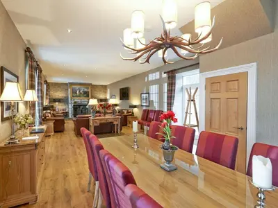 a dining room with a long table and red chairs at Home Farm Cottages, Glendaruel, Argyll. Scotland in Clachan of Glendaruel