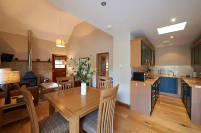 a kitchen and living room with a wooden table and chairs at Home Farm Cottages, Glendaruel, Argyll. Scotland in Clachan of Glendaruel
