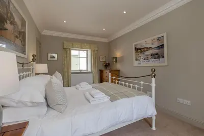 a bedroom with a white bed and a window at Home Farm Cottage in Stranraer