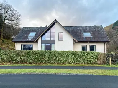 a white house with a black roof at The Beach House Loch Lomond in Luss