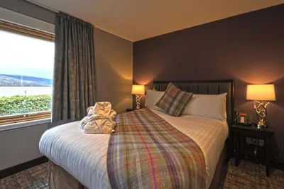 a teddy bear sitting on a bed in a hotel room at The Beach House Loch Lomond in Luss