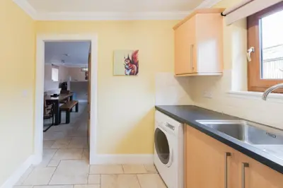 a kitchen with a sink and a washing machine at The Old Byre with Hot Tub in Forgandenny