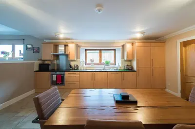 a large kitchen with a wooden table and a large table at The Old Byre with Hot Tub in Forgandenny