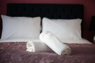 a couple of rolled towels sitting on a bed at Stunning One bed with parking in City Centre in Glasgow