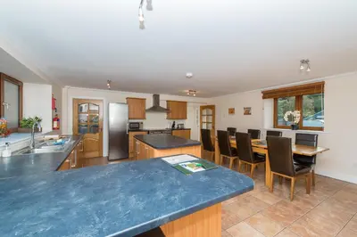 a large kitchen with a blue counter top and a table at The Granary with Hot Tub in Forgandenny