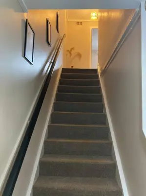 a stairway with some stairs with some pictures on the wall at Budget friendly apartment with stairs Near Glasgow airport and Loch Lomond in Clydebank