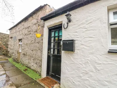 a white building with a black door and a bucket at The Coach House in Oban