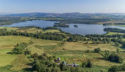 an aerial view of a lake and a house at Gamekeeper's Lodge- a cottage with a spectacular view in Port of Menteith