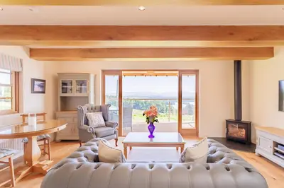 a living room with a couch and a table at Gamekeeper's Lodge- a cottage with a spectacular view in Port of Menteith