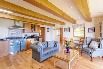 a living room with two couches and a table at Gamekeeper's Lodge- a cottage with a spectacular view in Port of Menteith