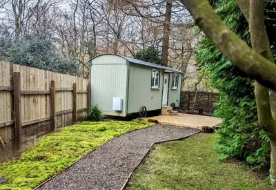 a small green trailer sitting in a yard next to a fence at The Best Moments Start Here in Corrie