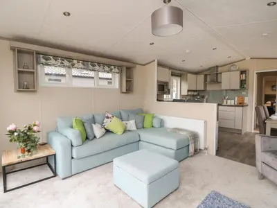 a living room with a blue couch and a kitchen at Rowan in Crieff