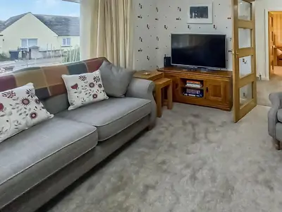 a living room with a couch and a flat screen tv at The Shieling in Biggar
