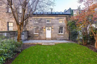 an old stone house with a yard and a white door at Dragon Suites - Yukina Suite - 2 bed city centre house with garden in Edinburgh