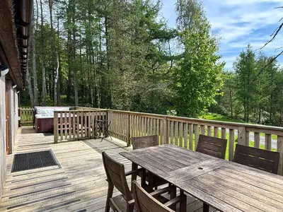 a wooden deck with a wooden table and chairs at Lord Galloway 31 with Hot Tub in Newton Stewart