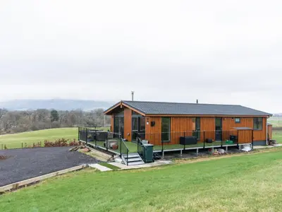 a large wooden house with a large yard at Chalet Loch Leven Lodge 25 East by Interhome in Kinross