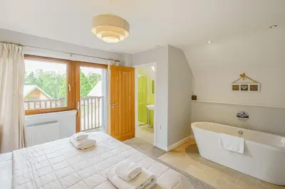 a bathroom with a tub and a large window at Lord Galloway 32 with Hot Tub in Newton Stewart