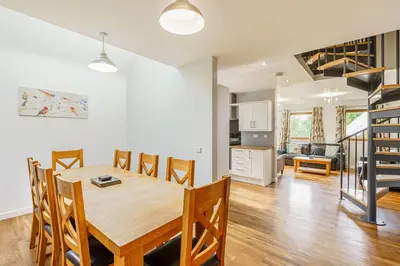 a dining room and living room with a table and chairs at Lord Galloway 33 with Hot Tub in Newton Stewart