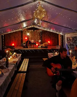 a man playing a guitar in front of a stage at Ranch House in Newton Stewart