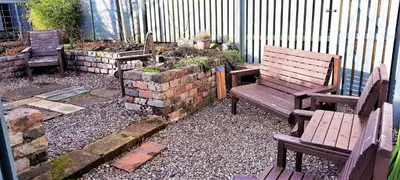 two wooden benches sitting in a garden with rocks at Greenbrae East in Crieff