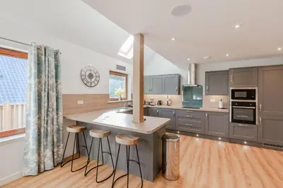 a kitchen with gray cabinets and a island with stools at Lord Galloway 38 with Hot Tub in Newton Stewart