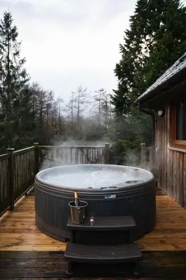 a hot tub sitting on a deck with a candle at Lord Galloway 38 with Hot Tub in Newton Stewart