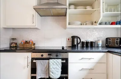 a kitchen with white cabinets and a stove top oven at Ochil View Holiday Let in Tullibody