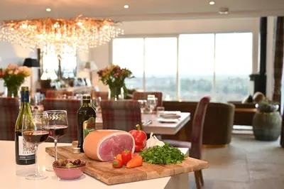 a table with a plate of food and glasses of wine at Kipney Farmhouse with hot tub in Perth