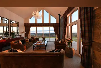 a living room with couches and a table and windows at Kipney Farmhouse with hot tub in Perth
