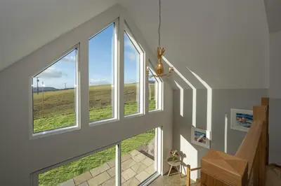 an attic hallway with large windows and a staircase at Lapwing - Stylish one bedroom country steading in Perth
