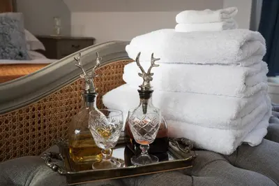 two bottles and glasses on a tray next to towels at Pigeon Cottage - Luxury country steading in Perth