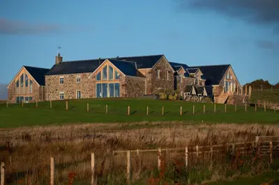 a large stone house in a field with a fence at Pigeon Cottage - Luxury country steading in Perth