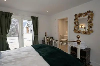 a bedroom with a bed with a mirror and a window at Capercaillie Cottage - Luxury converted steading in Perth