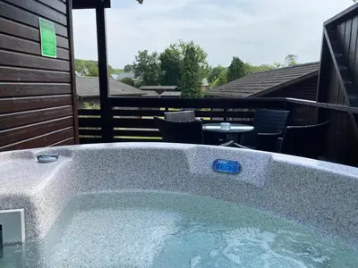a hot tub on a deck with a table and chairs at Birch Lodge 17 with Hot Tub in Newton Stewart