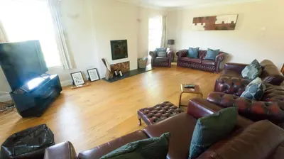 a living room with leather couches and a flat screen tv at The Byre in Strathyre