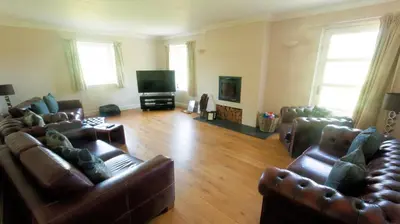 a living room with leather furniture and a flat screen tv at The Byre in Strathyre