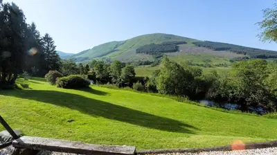a field of grass with a mountain in the background at The Byre in Strathyre