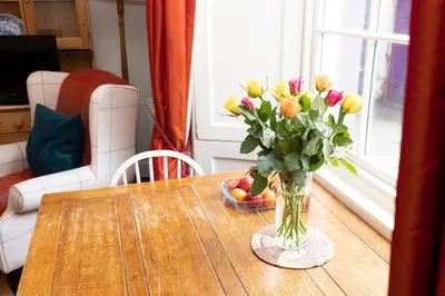 a vase of flowers on a table with a bowl of fruit at Charming Hideaway in Edinburgh City Centre in Edinburgh