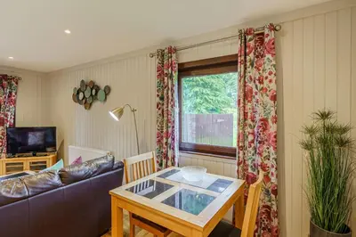 a living room with a table and a couch at Bluebell Lodge 10 with Hot Tub in Newton Stewart