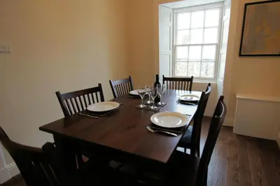 a dining room table with chairs and a wooden table with glasses at Comrie Old Schoolhouse in Comrie